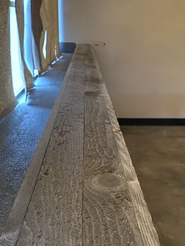 Luxury vinyl plank flooring with realistic wood grain texture running along an interior wall beside windows.